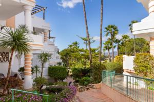 un bâtiment blanc avec des palmiers et des plantes dans l'établissement Matchroom Country Club Resort, à Fuengirola