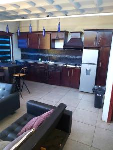 a large kitchen with a couch and a refrigerator at Hotel Monte Campana Heredia in Birrí