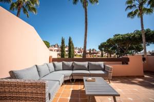 ein Sofa und einen Tisch auf einer Terrasse mit Palmen in der Unterkunft Villa Simone by Intiholidays in Quarteira