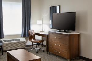 a hotel room with a desk and a flat screen tv at Wingate by Wyndham Hurricane WV in Hurricane +32 photos