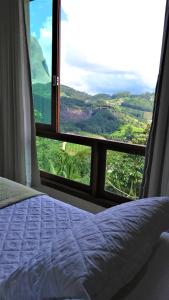 um quarto com uma cama e uma janela com vista em Apto Residencial Vista Azul - Pedra Azul - ES em Domingos Martins