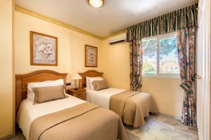 two beds in a room with a window at Macdonald Doña Lola Resort in La Cala de Mijas