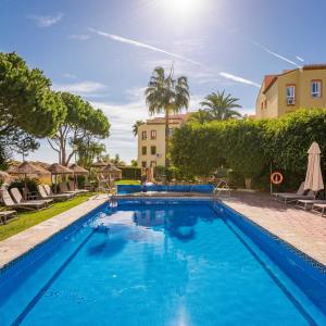 a swimming pool in a resort with trees and a building at Macdonald Doña Lola Resort in La Cala de Mijas