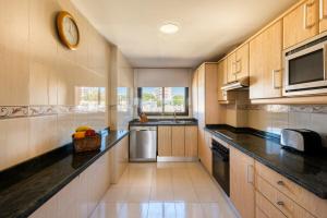 a kitchen with wooden cabinets and black counter tops at Macdonald Doña Lola Resort in La Cala de Mijas
