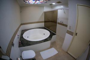 a bathroom with a tub and a shower and a toilet at Chale Motel in Paulínia