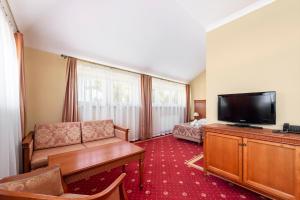 uma sala de estar com um sofá e uma televisão de ecrã plano em Hotel Stodółka em Kielce