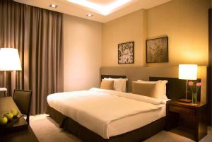 金夏沙的住宿－Kin Plaza Arjaan by Rotana，酒店客房设有一张大床和两盏灯。