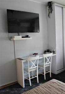 une table blanche avec deux chaises et une télévision murale dans l'établissement Apartment Skadarlija, à Belgrade