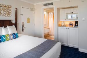 a small bedroom with a bed and a kitchen at Island Grand at TradeWinds in St. Pete Beach