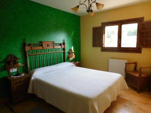 1 dormitorio con cama blanca y paredes verdes en Las Hoyas I y II en Tolbaños de Arriba