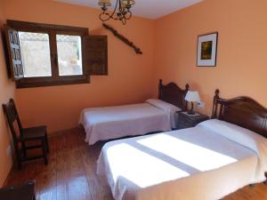 1 dormitorio con 2 camas y ventana en Las Hoyas I y II, en Tolbaños de Arriba