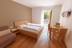 a bedroom with a bed and a table and a chair at BNB Garni Kreithof in Caldaro