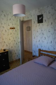 een slaapkamer met een bed en een muur met bloemenbehang bij Les Locations de Lara IV - T2 spacieux Parking privatif Près port, plage, Ile des Loisirs in Cap d'Agde