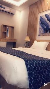 a bedroom with a bed with a blue and white blanket at Juri Ahla Al Masayef Furnished Units in Taif