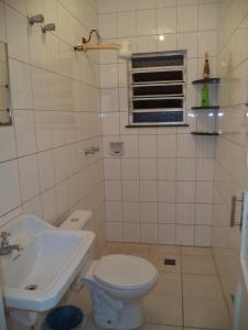 biała łazienka z toaletą i umywalką w obiekcie Jóias Preciosas- Kitnet Mobiliado w mieście Campinas