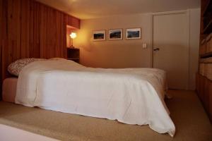um quarto com uma cama com um cobertor branco em RASCAS Gîte de Montagne em Briançonnet