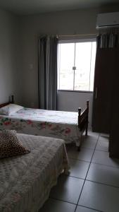 two beds in a room with a window at Apartamento na Praia de Enseada in São Francisco do Sul