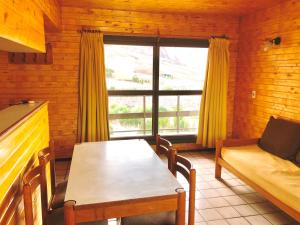 a living room with a table and a couch and a window at Apartur Las Leñas in Las Lenas