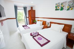 two beds in a hotel room with white sheets at Thy Hung legacy hotel in Tuy Hoa