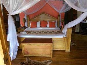 um quarto com uma cama grande e almofadas vermelhas em Trackers Safari Lodge Bwindi em Buhoma