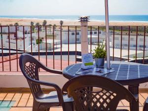 een tafel en stoelen op een balkon met uitzicht op het strand bij ConilPlus apartment SANTA CATALINA II in Conil de la Frontera