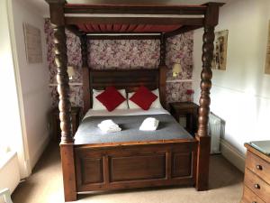 a bedroom with a canopy bed with red pillows at Gomersal Lodge Hotel in Cleckheaton +16 photos