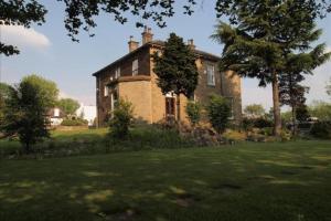 uma grande casa de tijolos num campo de relva em Gomersal Lodge Hotel em Cleckheaton