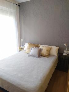 een slaapkamer met een bed met witte lakens en kussens bij APARTAMENTO BEATRIZ in Pobra do Caramiñal