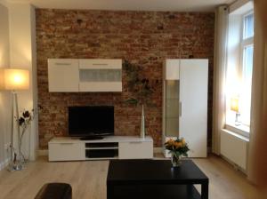 a living room with a tv and a brick wall at 2-Zimmer Ferienwohnung im Herzen von Scheeßel in Scheeßel