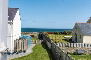 a house with a fence and the ocean in the background at Penrhyn Cottage in Cemaes Bay