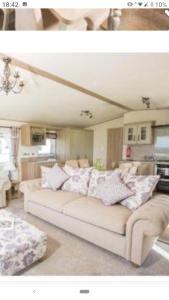 una sala de estar con un sofá blanco con almohadas en Valley View with a luxurious hot tub, en Newquay