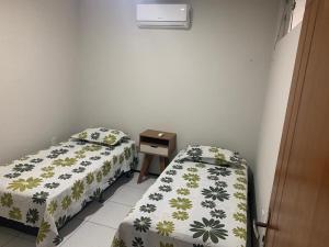 ein Schlafzimmer mit zwei Betten und einem Nachttisch mit Bettvolant in der Unterkunft Pousada Residencial Milagre 101 in Juazeiro do Norte