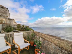 a balcony with two chairs and a view of the ocean at 8 Coastguard Cottages in Dawlish