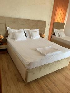 1 dormitorio con 1 cama grande con sábanas y almohadas blancas en Vila Mimoza, en Eforie Nord