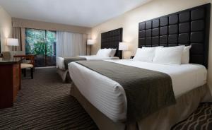 a hotel room with two beds and a desk at Prestige Vernon Lodge in Vernon