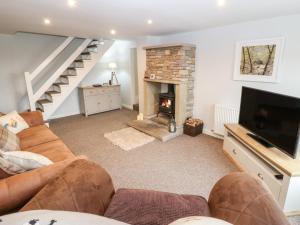 ein Wohnzimmer mit einem Sofa und einem Kamin in der Unterkunft Wren Cottage in Oldham