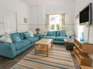 a living room with blue couches and a tv at Gull Cottage in Tintagel