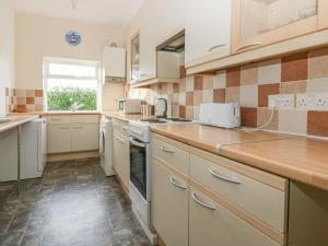 a kitchen with white cabinets and a counter top at Gull Cottage in Tintagel