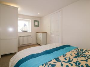 Un dormitorio con una cama y una ventana con un velero. en Cove Cottage, en Tintagel