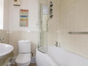 Un baño con inodoro, bañera y lavabo. en Cove Cottage, en Tintagel