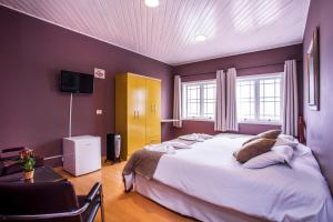 um quarto com uma cama grande e uma TV em Grand Residences Pousadas em Campos de Jordão