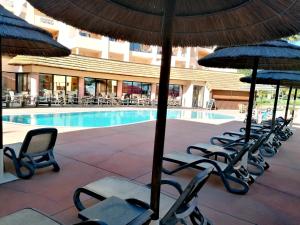 a group of chairs and umbrellas next to a pool at Praia da Luz Monique Apartment in Luz