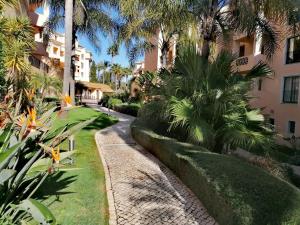 a walkway in front of a building with palm trees at Praia da Luz Monique Apartment in Luz
