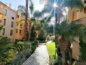 a walkway through a courtyard with palm trees at Praia da Luz Monique Apartment in Luz