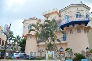 un grand bâtiment avec un palmier devant dans l'établissement Caribe Apartament S&D el castillo dominicus Apartamento #9, à Bayahibe