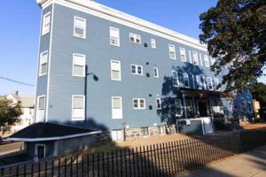 a large blue building with a fence in front of it at Stylish Apartment in Malden. 20 min from Boston in Malden