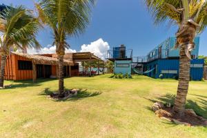 uma casa com duas palmeiras e um parque infantil em Eco Hostel & Suítes em São Miguel do Gostoso