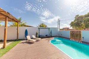 a backyard with a swimming pool and a wooden deck at Eco Hostel & Suítes in São Miguel do Gostoso