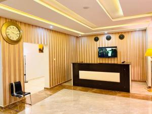 アブジャにあるMayFair Hotel Maitama Abujaの壁に時計、テレビが備わる客室です。