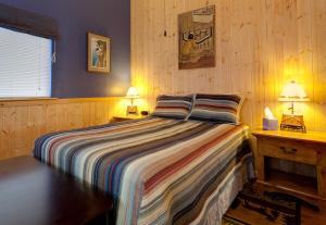a bedroom with a bed and a table and two lamps at Sea Parrot Inn in Seldovia